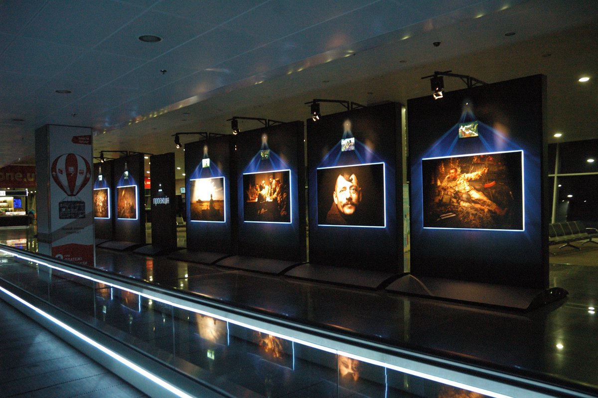 Reminders in Ukraine's Boryspil airport about Russian proxy aggression: the monitor from destroyed Donetsk airport  and  the photo exhibit.  