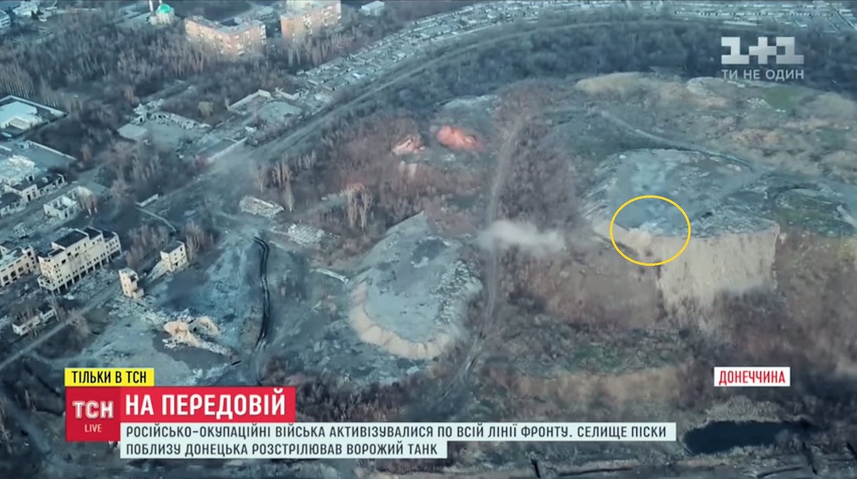 Ukrainian drone spots Russian tank firing on village of Pisky. From Russian occupied Donetsk, to get an elevated firing position, tank has driven up a large mine, slag heap. Pisky's been devastated by Russian artillery.