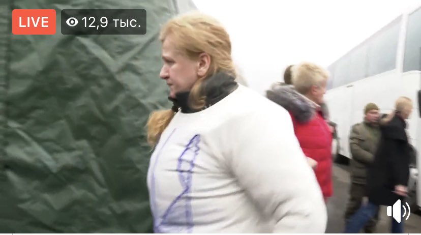 One of released prisoners, Ukrainian woman in jacket with handmade Trident and Ukraine is my country 