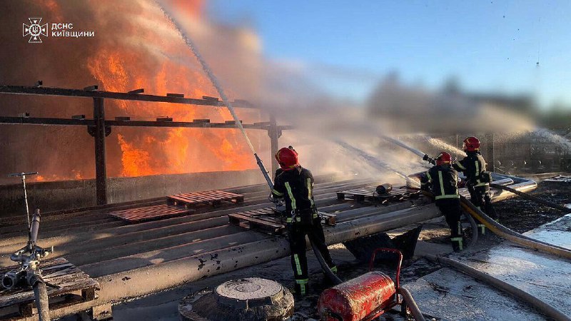 Bombeiros na região de Kyiv extinguindo o incêndio em uma empresa industrial, causado por destroços de um míssil russo por um dia